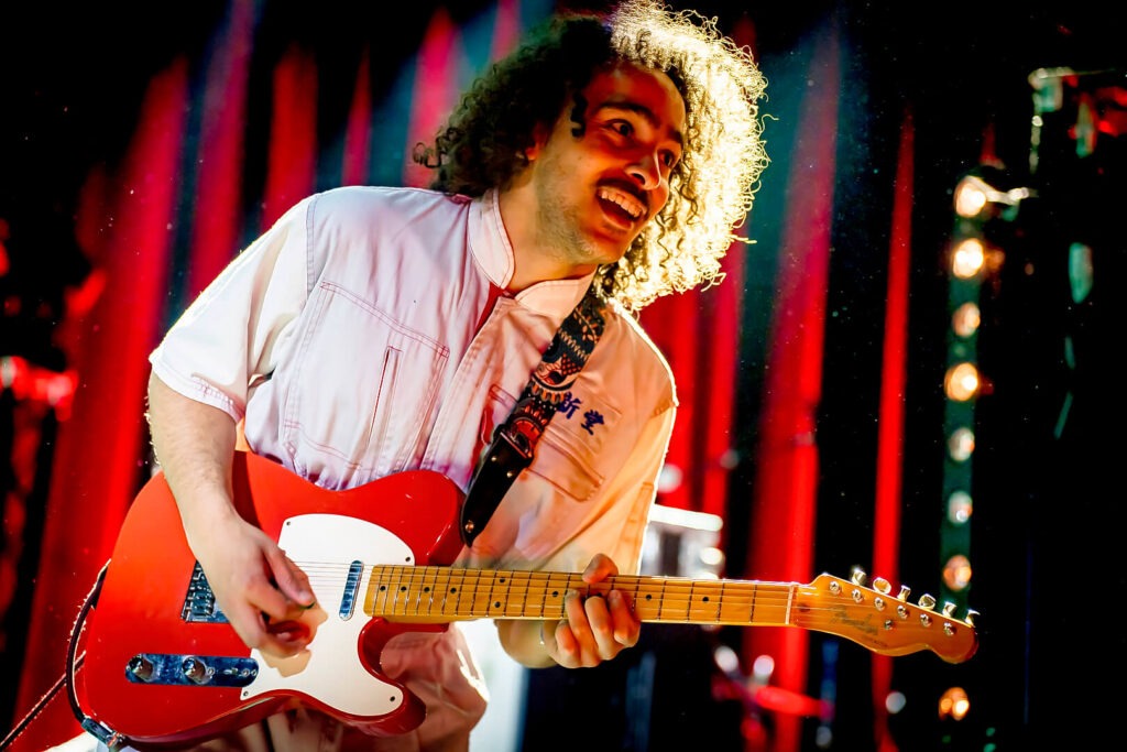 Gitarrist spielt auf Bühne mit roter Gitarre