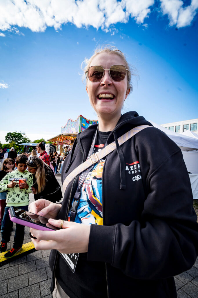 Lächelnde Person auf Jahrmarkt mit Smartphone