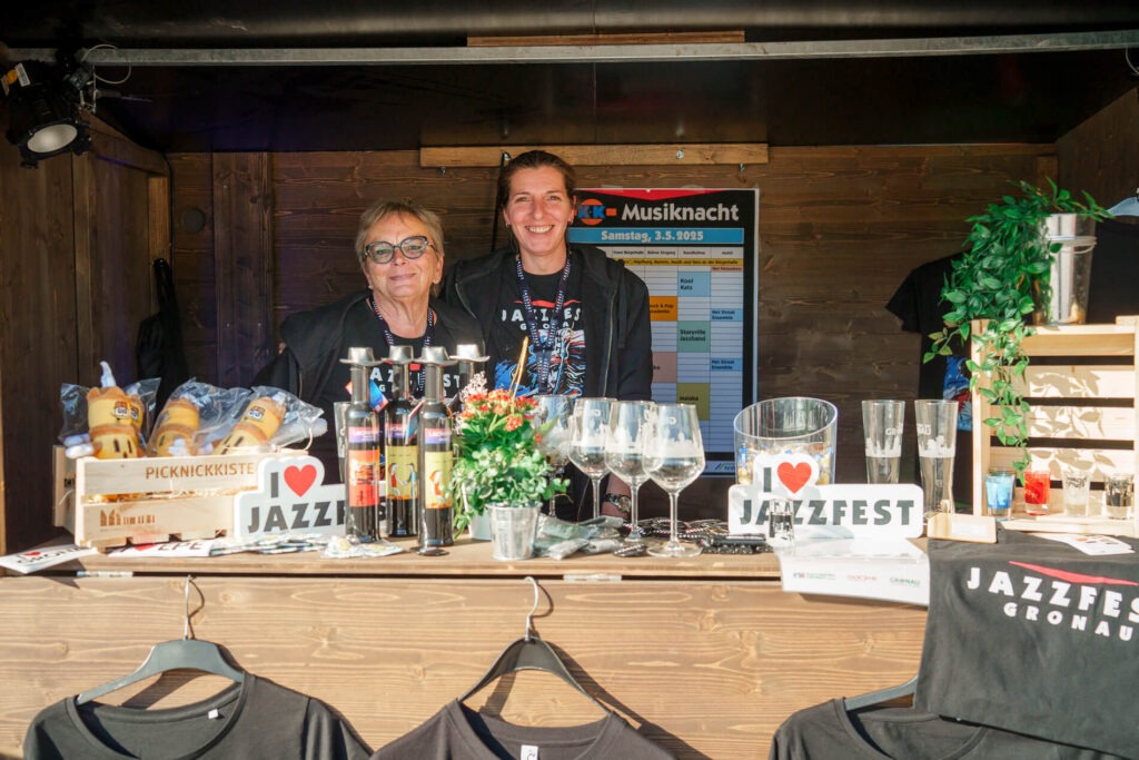Zwei Personen an einem Jazzfest-Stand mit Dekorationen.