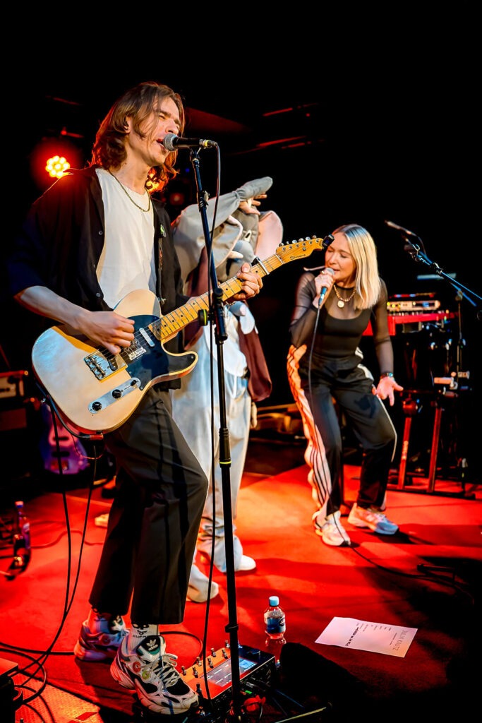 Zwei Musiker beim Auftritt auf der Bühne, Mikrofone und Gitarre.