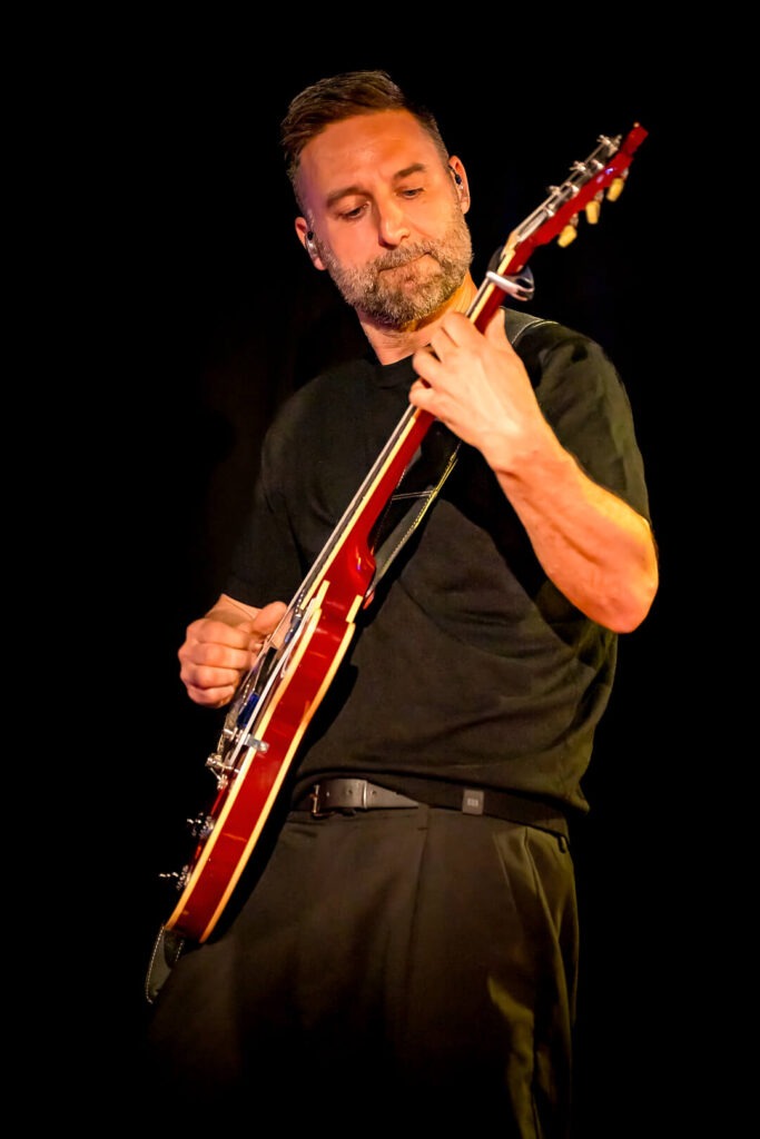 Mann spielt Gitarre auf der Bühne