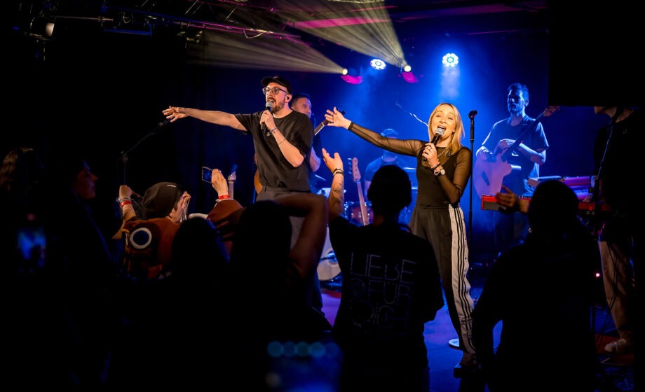 Konzert mit Sänger und Band auf der Bühne.