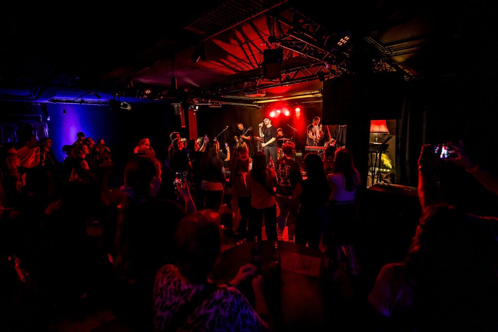 Konzert in einem beleuchteten Club mit Publikum.
