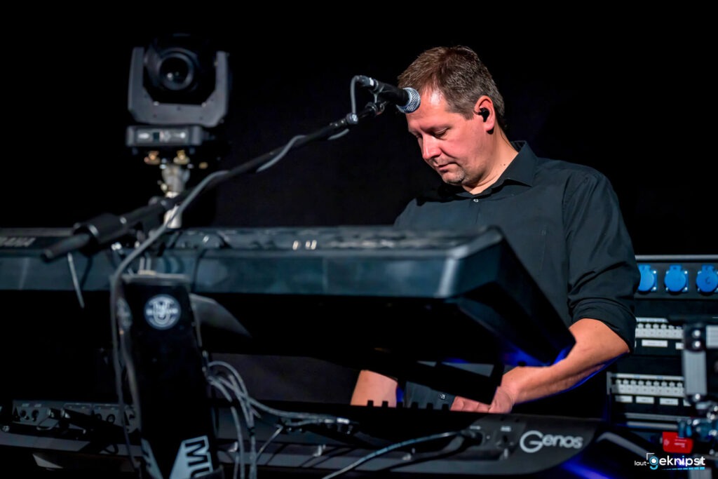 Mann spielt Keyboard auf Bühne mit Mikrofon