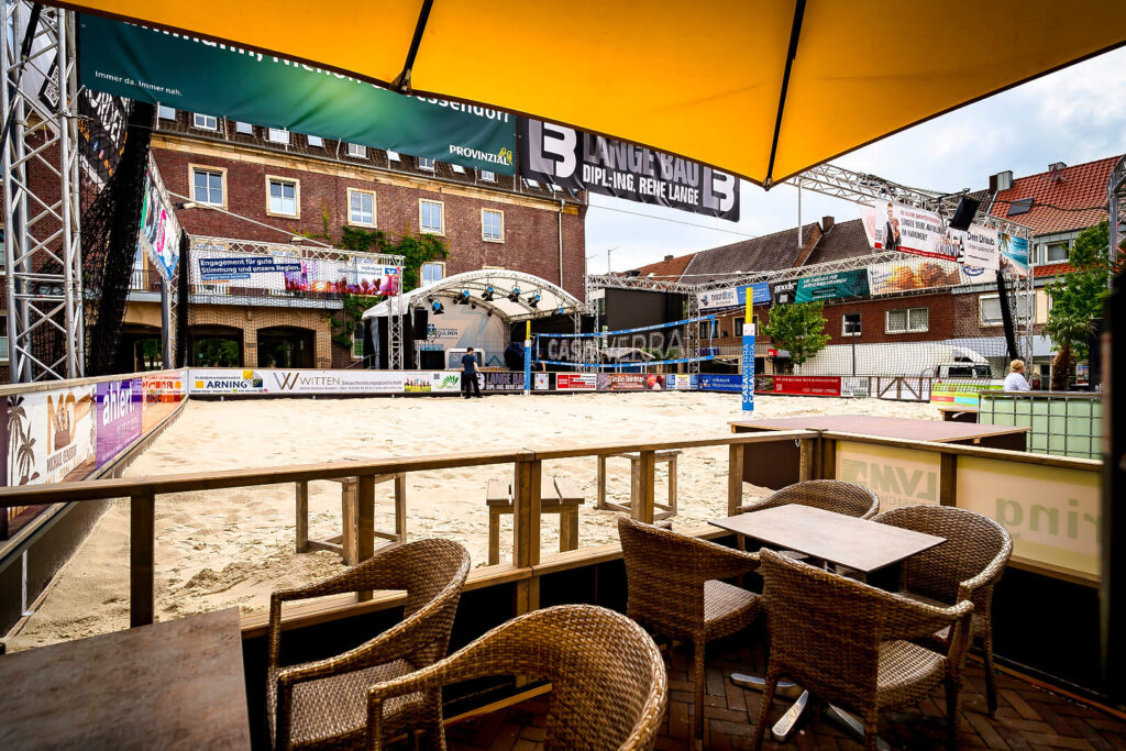 Sandplatz mit Bühne und Sitzbereich im Freien.