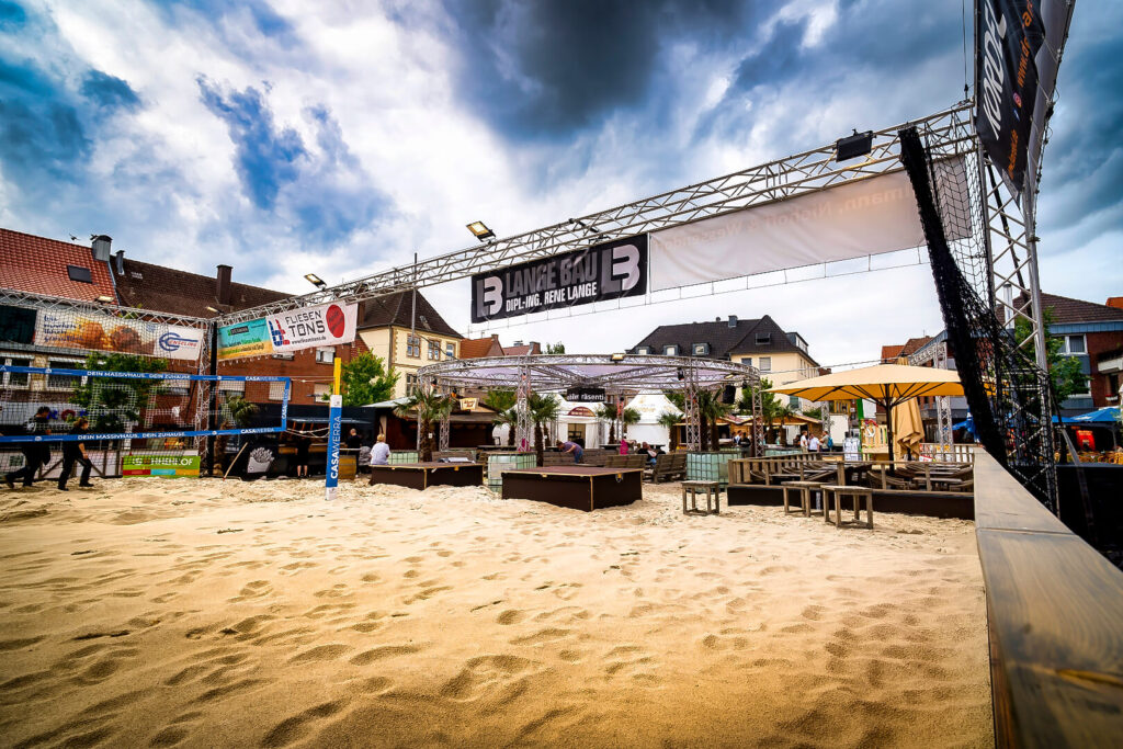 Outdoor-Eventbereich mit Beach-Volleyballplatz und Bühnenbereich.