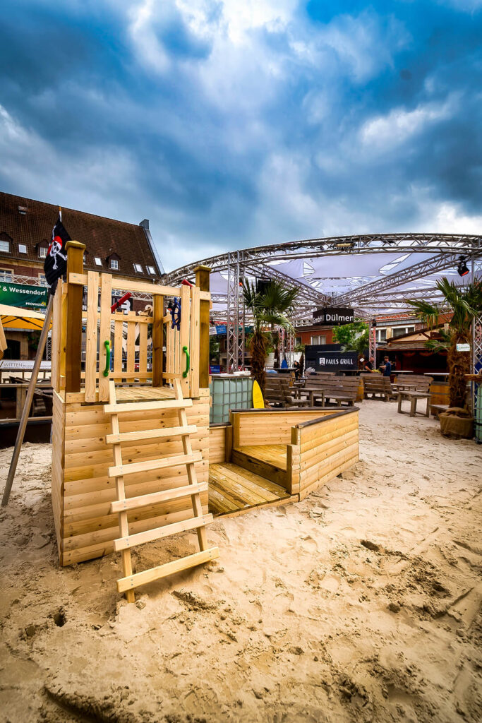 Holzspielplatz mit Sand und Palmen im Freien