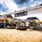 Städtisches Strandcafé mit Volleyballplatz und Sitzbereich.