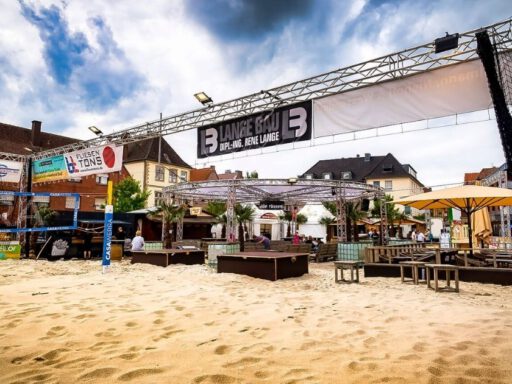 Städtisches Strandcafé mit Volleyballplatz und Sitzbereich.
