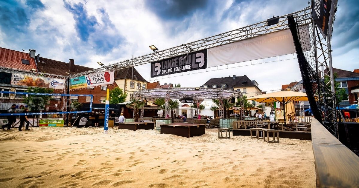 Städtisches Strandcafé mit Volleyballplatz und Sitzbereich.