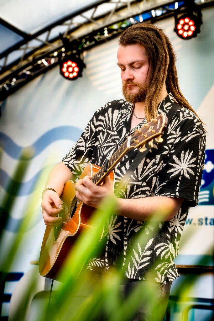 Mann spielt Gitarre auf einer Bühne.