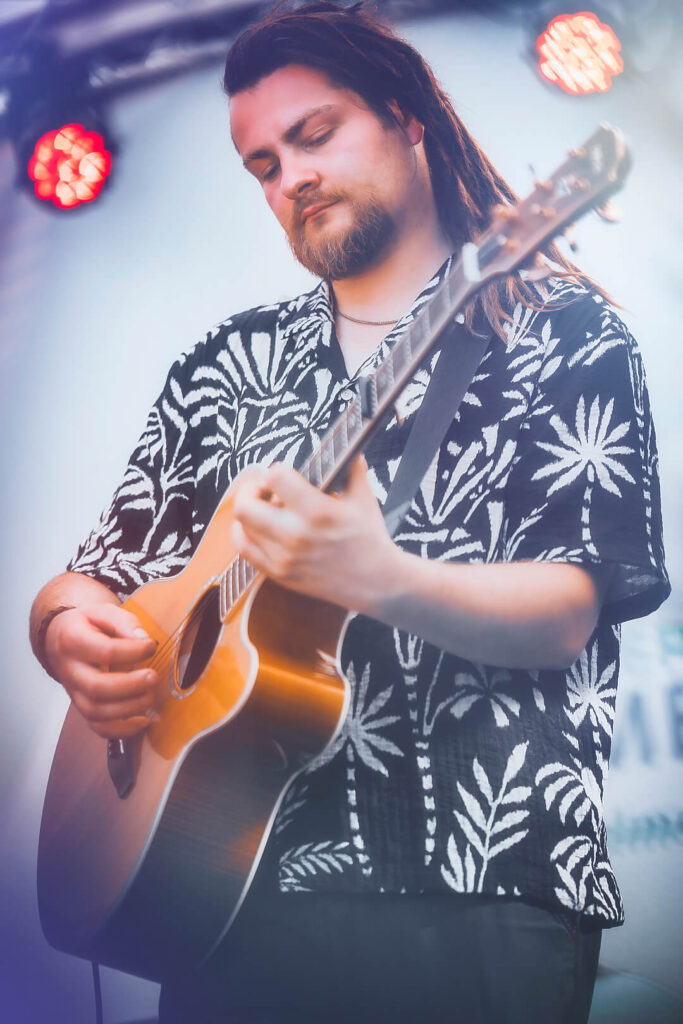 Mann spielt akustische Gitarre auf der Bühne.