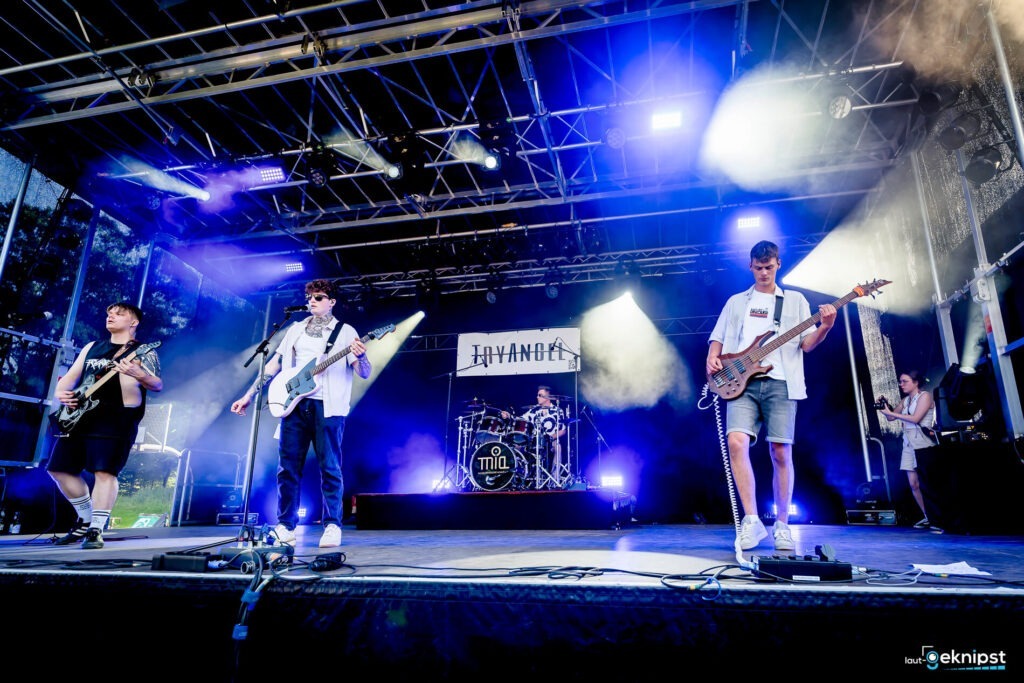 Band spielt auf offener Bühne mit Lichtern.