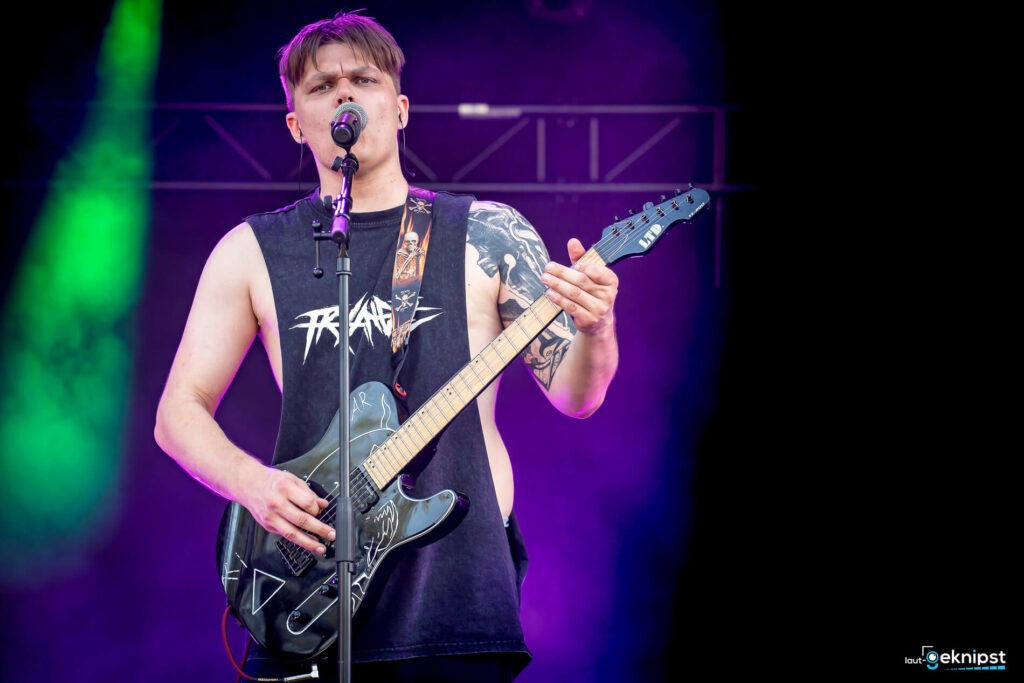 Musiker spielt E-Gitarre auf der Bühne.
