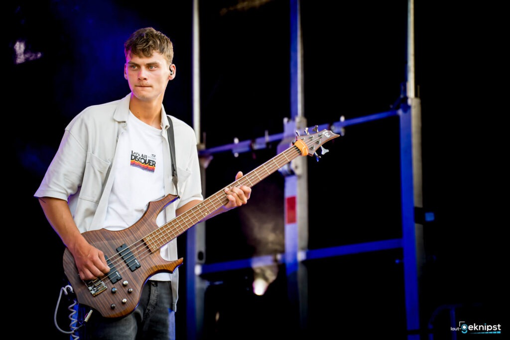 Musiker spielt Bassgitarre auf der Bühne.