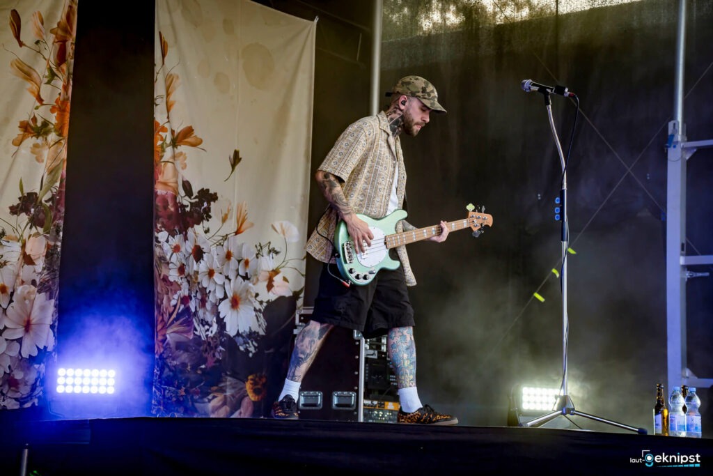 Bassist auf Bühne mit Blumenhintergrund