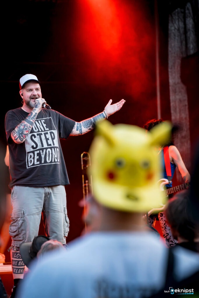 Mann singt auf der Bühne vor rotem Licht.