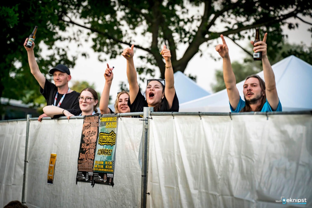 Jubelnde Festivalbesucher hinter einem Absperrzaun.