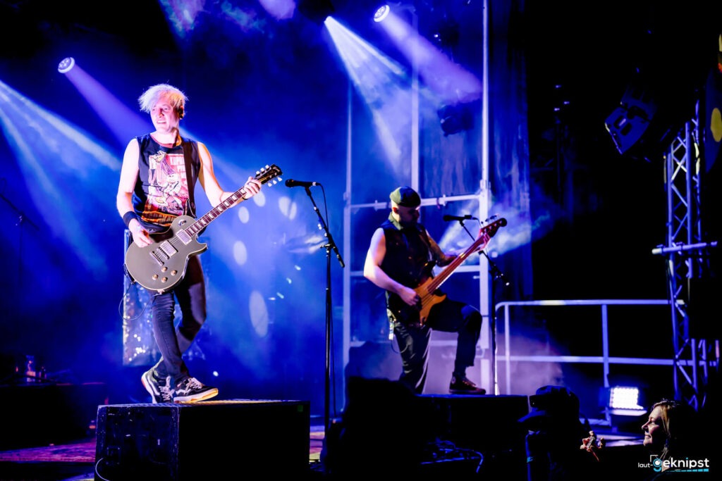 Rockband spielt auf einer Bühne mit Lichteffekten.