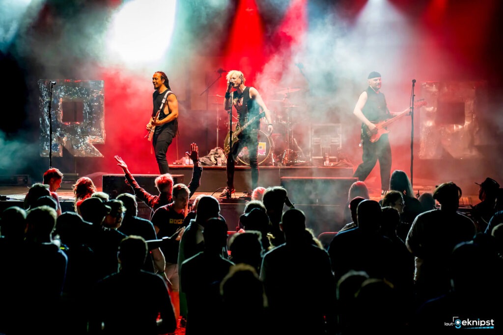 Rockband spielt vor Publikum mit rotem Licht.