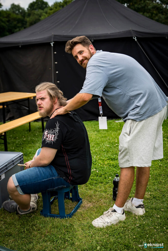 Mann erhält Massage im Freien, Zelt im Hintergrund.