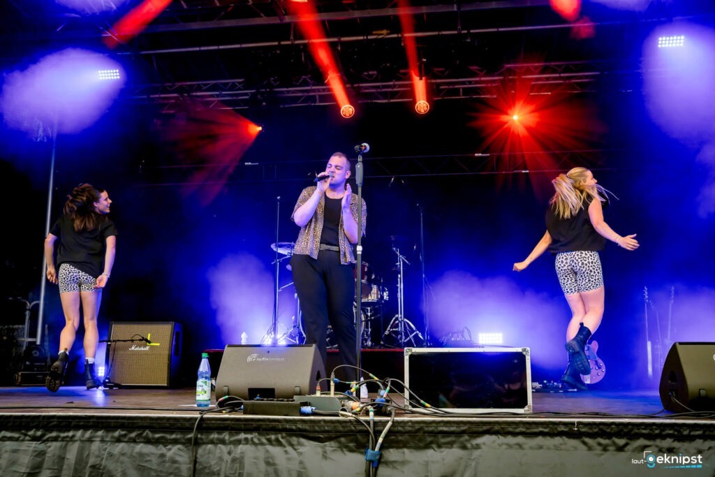 Live-Konzert mit Sänger und Tänzerinnen auf der Bühne.