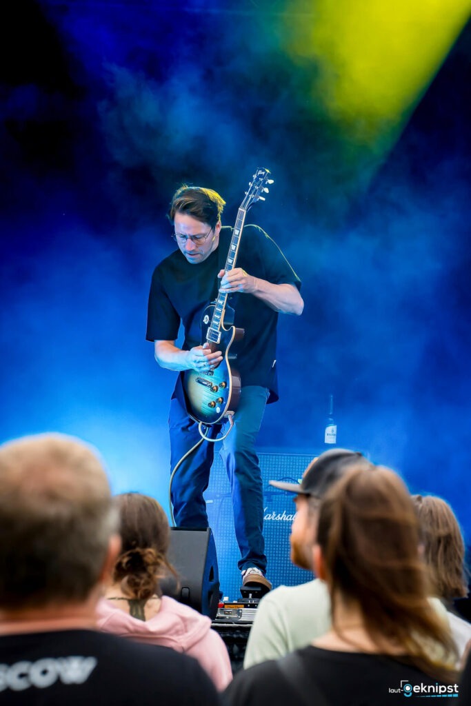 Gitarrist spielt auf einer Konzertbühne.