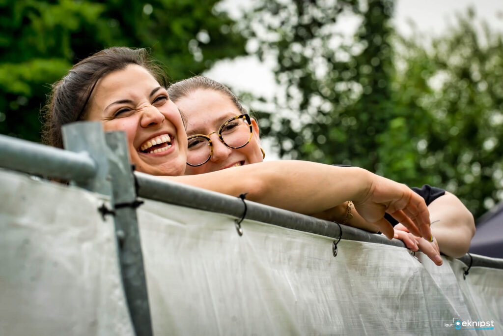 Zwei Frauen lachen hinter einem Zaun.