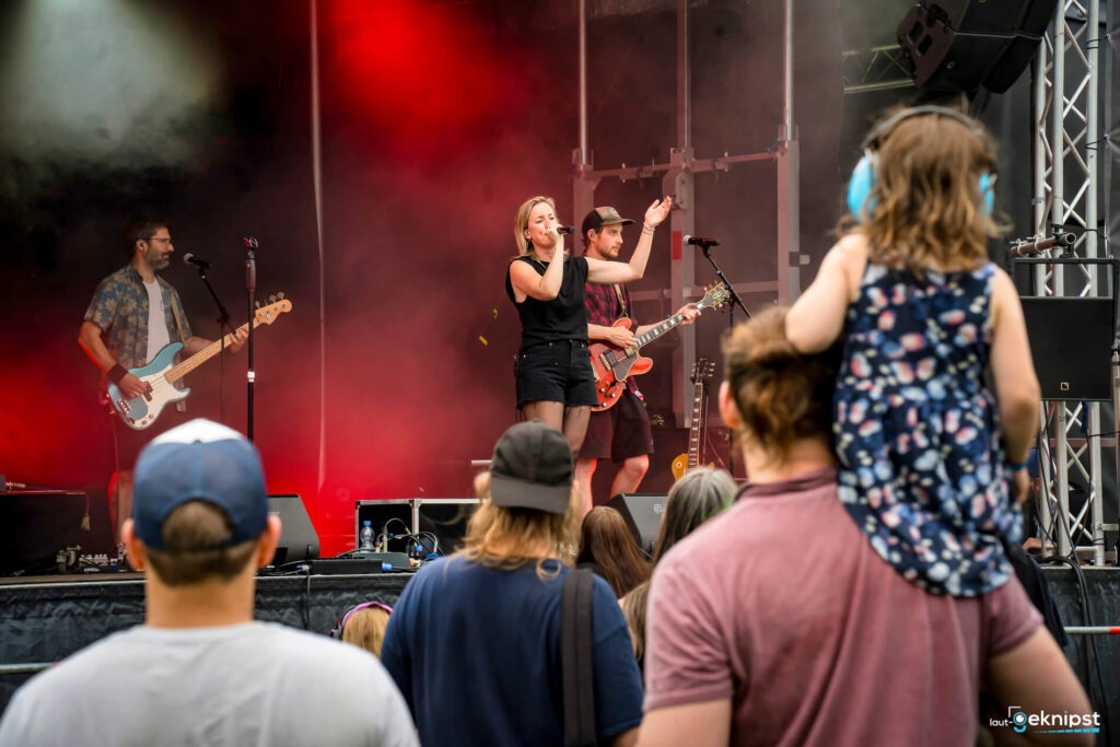 Konzertbühne mit Band und Publikum im Freien.