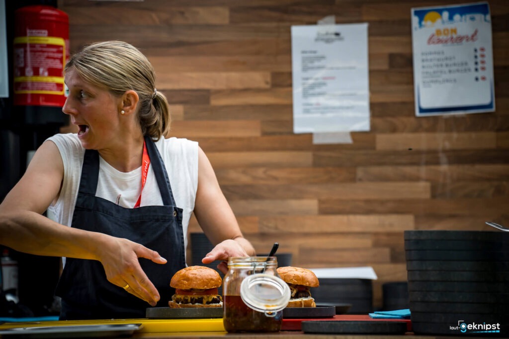 Frau bereitet Burger in einer Küche zu.