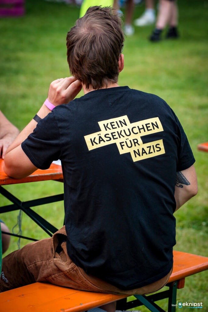 Mann mit Anti-Nazi-T-Shirt auf Festivalbank.