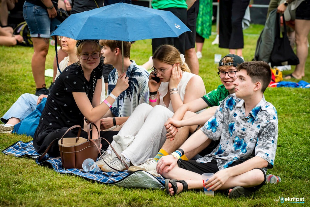 Gruppe von Personen mit Regenschirm auf einer Wiese