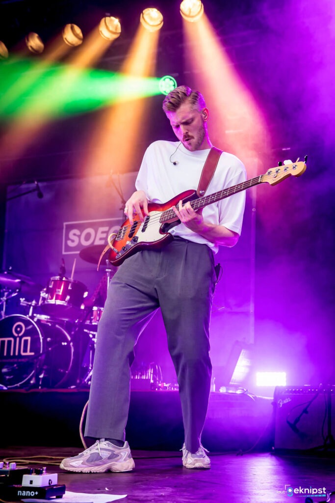 Bassist spielt auf der Bühne mit buntem Licht.