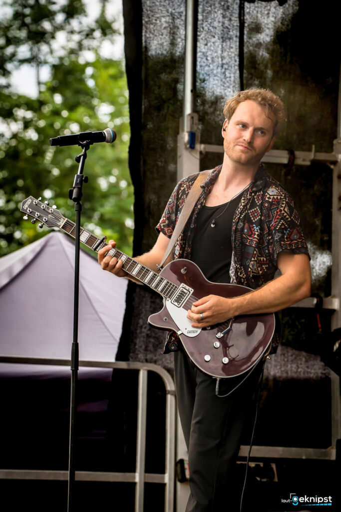 Musiker spielt Gitarre auf Open-Air-Bühne.