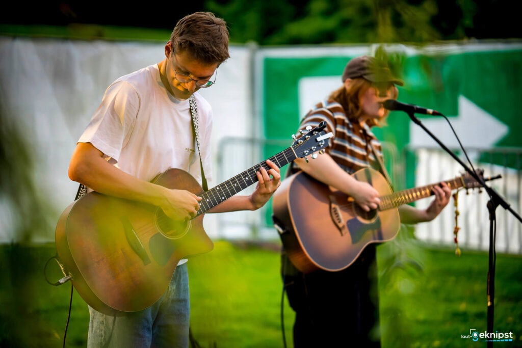 Zwei Musiker spielen Gitarren auf der Bühne.