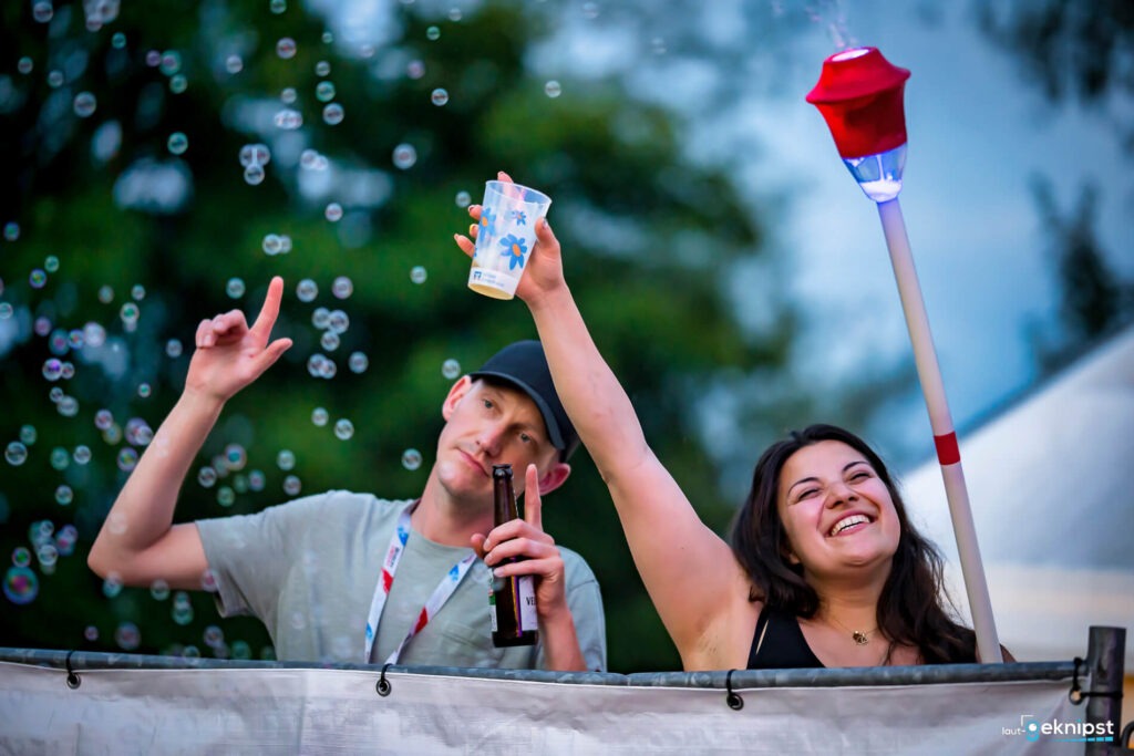 Lächelnde Personen bei einem Outdoor-Event mit Getränken.