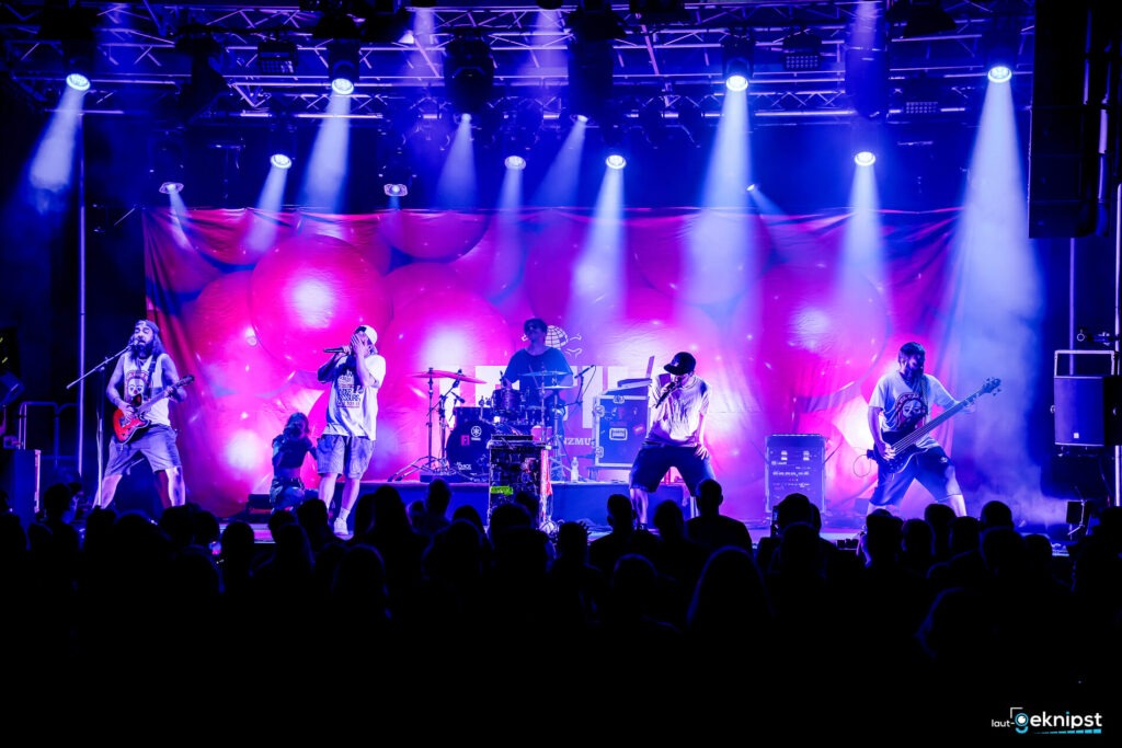 Band spielt Live-Konzert auf bunte Bühne.