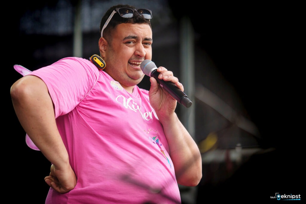 Mann im rosa T-Shirt singt mit Mikrofon