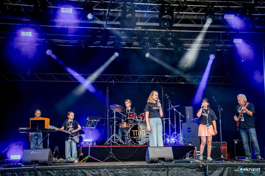 Band spielt auf Bühne mit Lichteffekten.