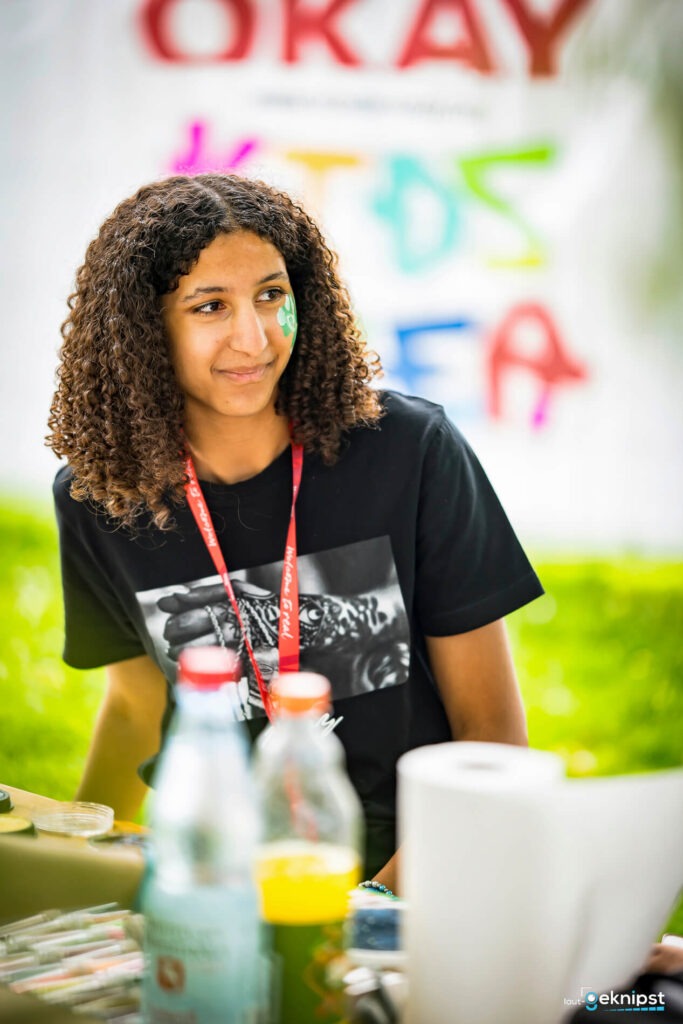 Junge Frau bei einem Festivalstand lächelt