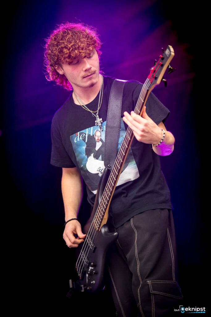 Musiker spielt Bassgitarre auf der Bühne.