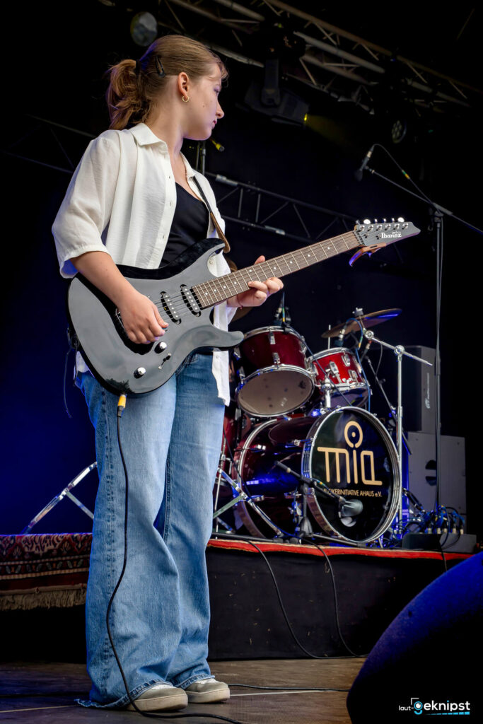 Frau spielt E-Gitarre auf Bühne
