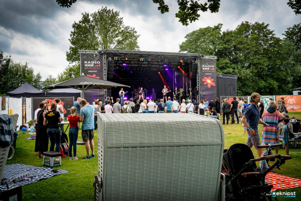 Open-Air-Konzert mit Bühne und Zuschauern im Park.