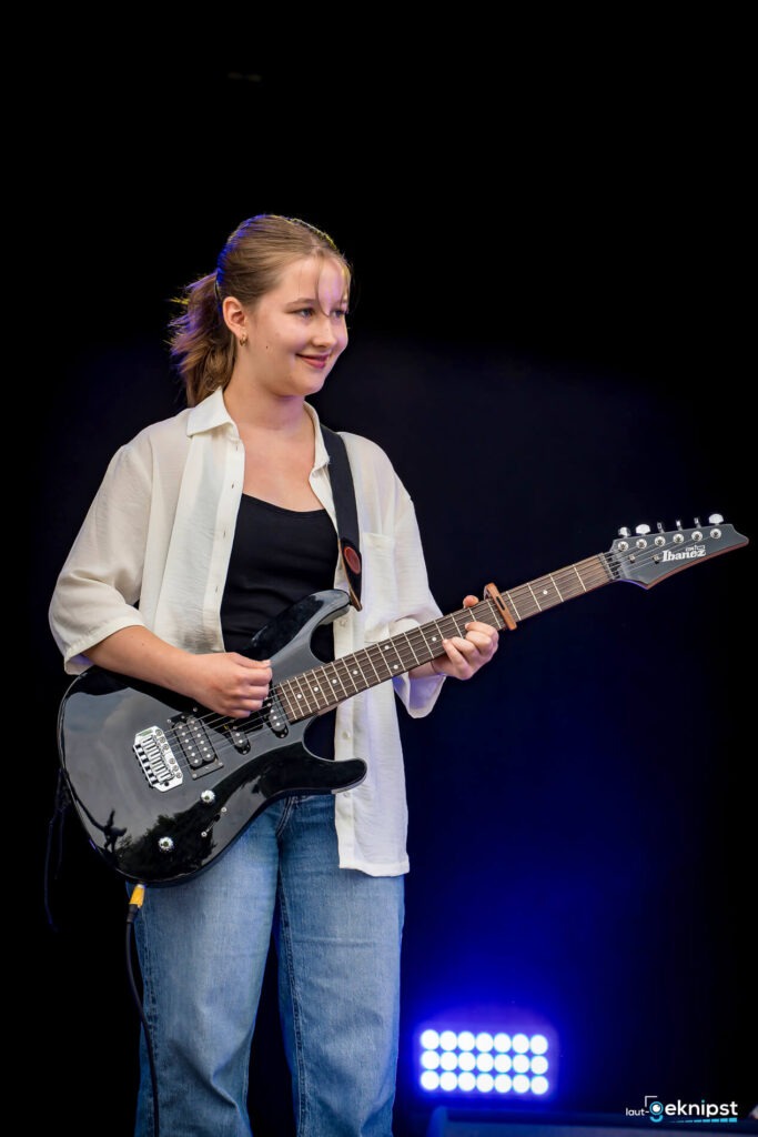 Person spielt E-Gitarre auf der Bühne.