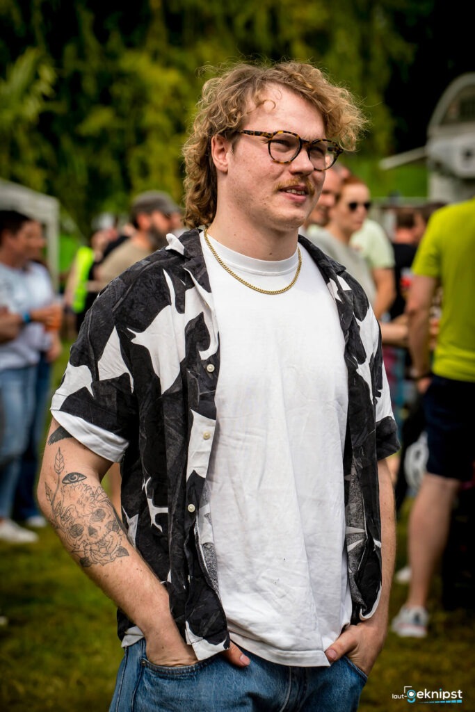 Person bei Outdoor-Event mit Brille und Tattoos