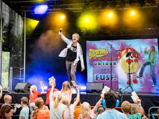 Mann singt auf Bühne, Kinder jubeln.
