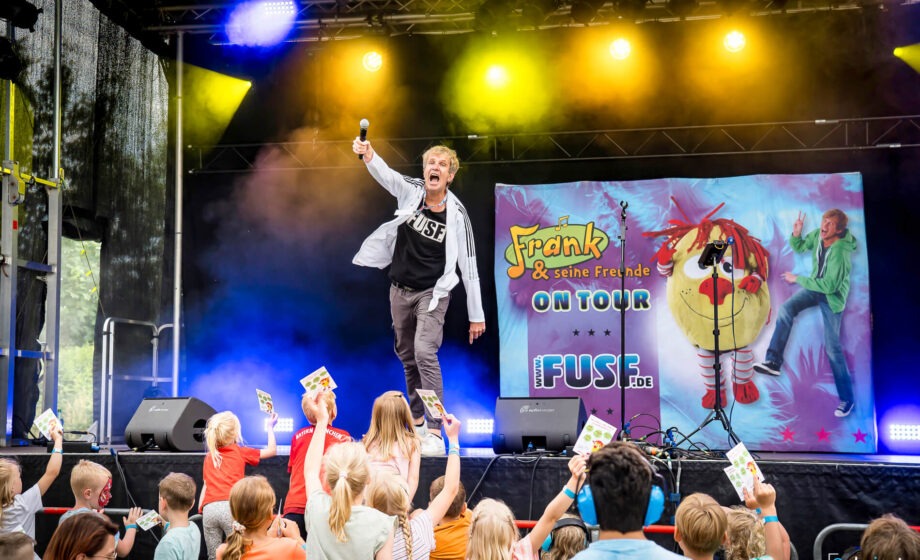 Mann singt auf Bühne, Kinder jubeln.