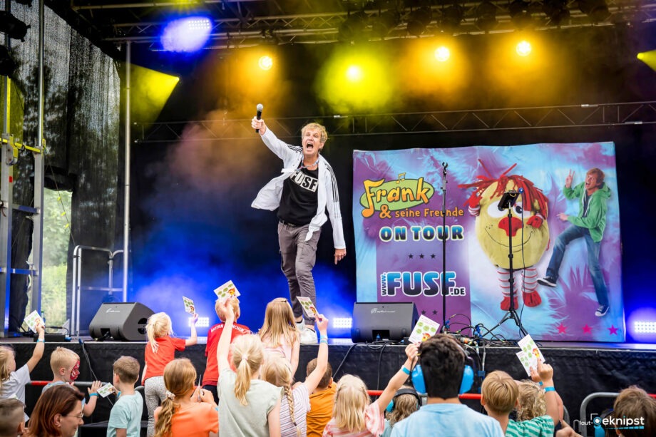 Mann singt auf Bühne, Kinder jubeln.