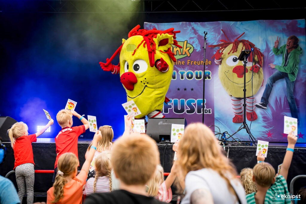 Kinder jubeln Maskottchen bei Veranstaltung zu.
