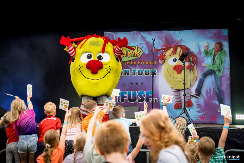 Kindershow mit großem gelbem Maskottchen und Kindern